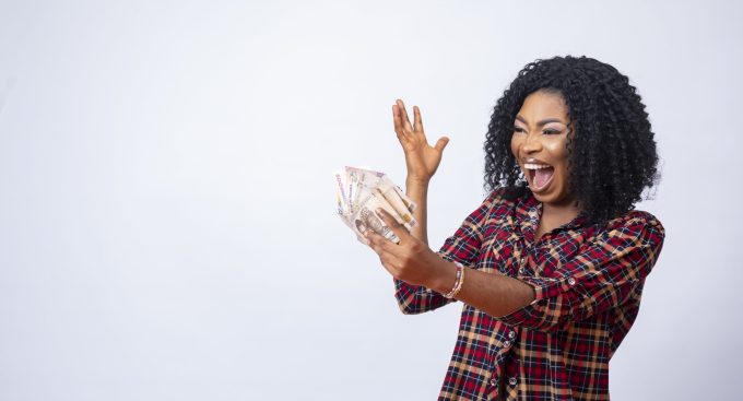 A beautiful black woman holding and looking at the money in her hand